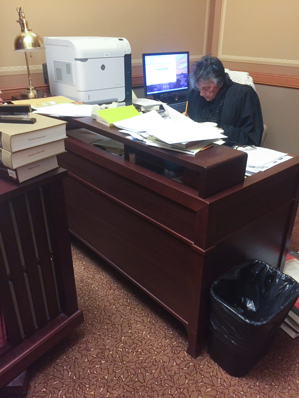 Justice Abrahamson, working at a paper-strewn desk